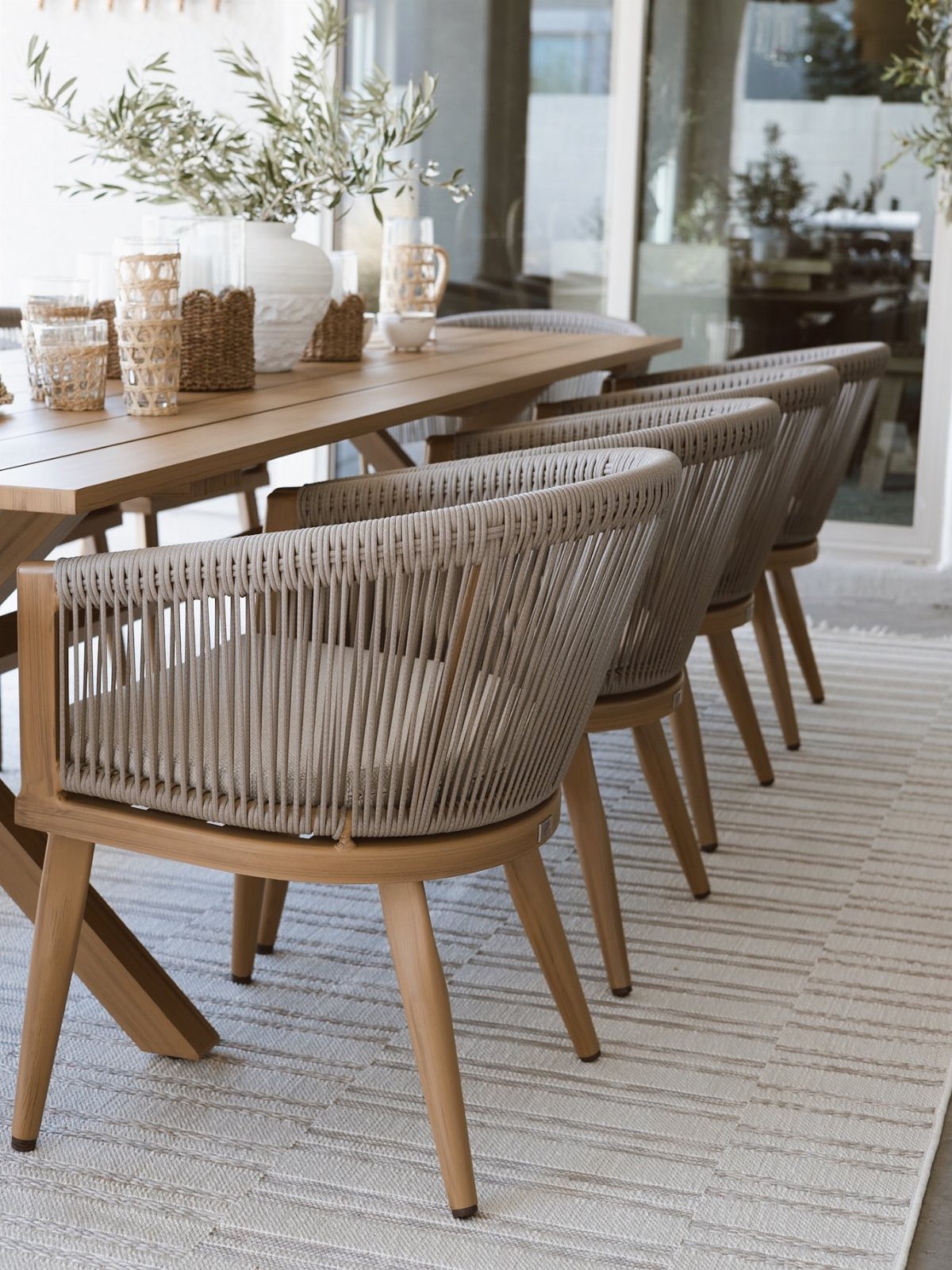 29 Scandinavian Outdoor Furniture for Patios and Gardens 24 Wooden outdoor dining table with woven rope chairs on a light grey rug.