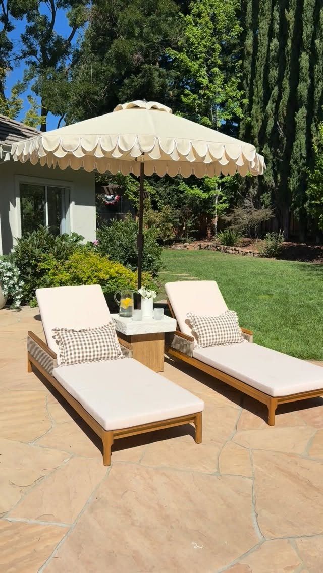 29 Scandinavian Outdoor Furniture for Patios and Gardens 26 Two wooden lounge chairs with cream cushions under a scalloped patio umbrella.