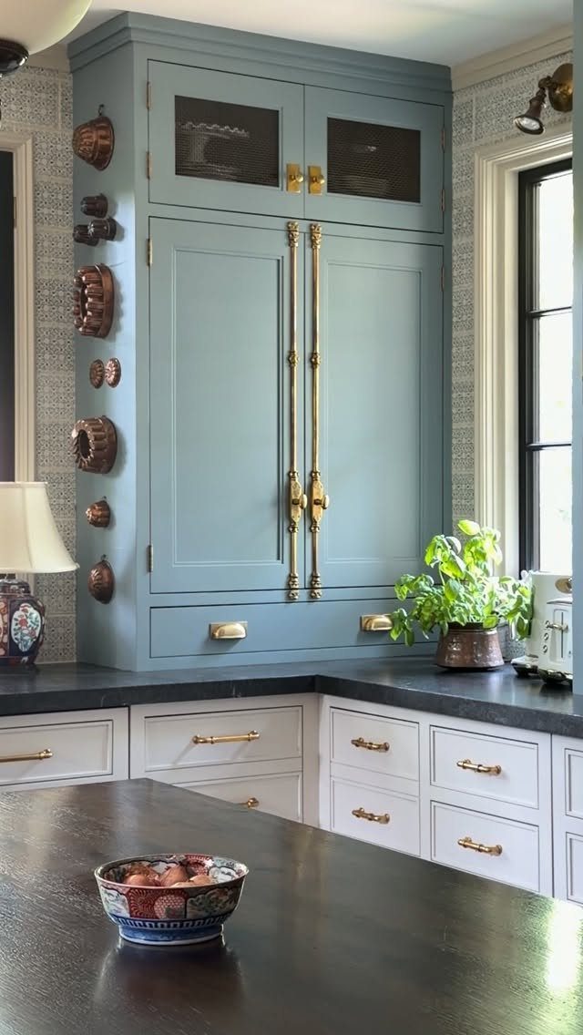 Light blue tall kitchen cabinet with gold hardware and white lower drawers.