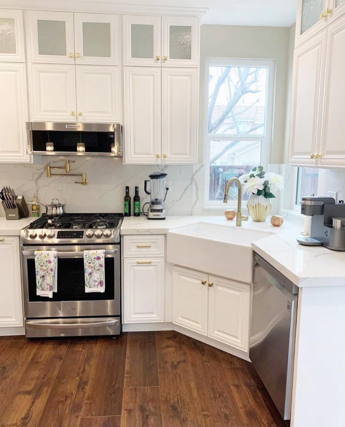 White U-shaped kitchen with farmhouse sink, shaker cabinets, and dark wood floors.