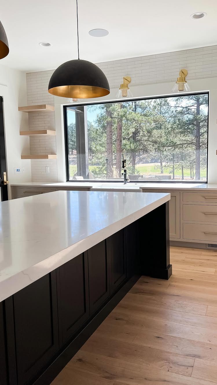 Kitchen sink centered under a large window with a view of pine trees.