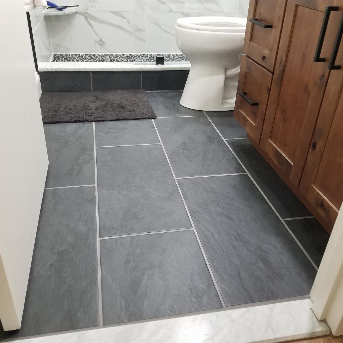 19 Teen Bathroom Ideas That Blend Style and Function 9 Dark grey porcelain floor tiles in a bathroom with a wooden vanity and toilet.