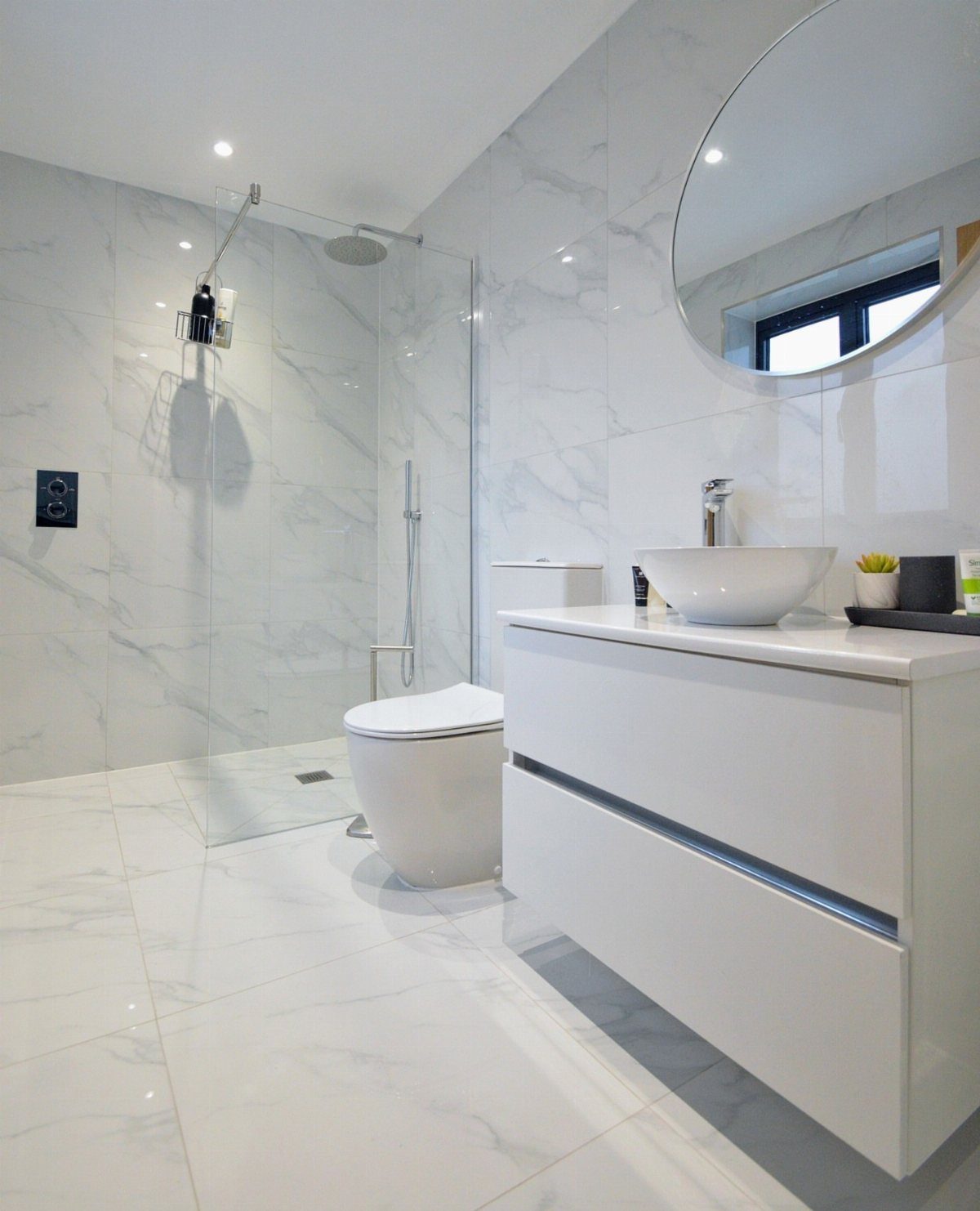 19 Teen Bathroom Ideas That Blend Style and Function 18 Bright white bathroom with marble tiles, floating vanity, and a round wall mirror.