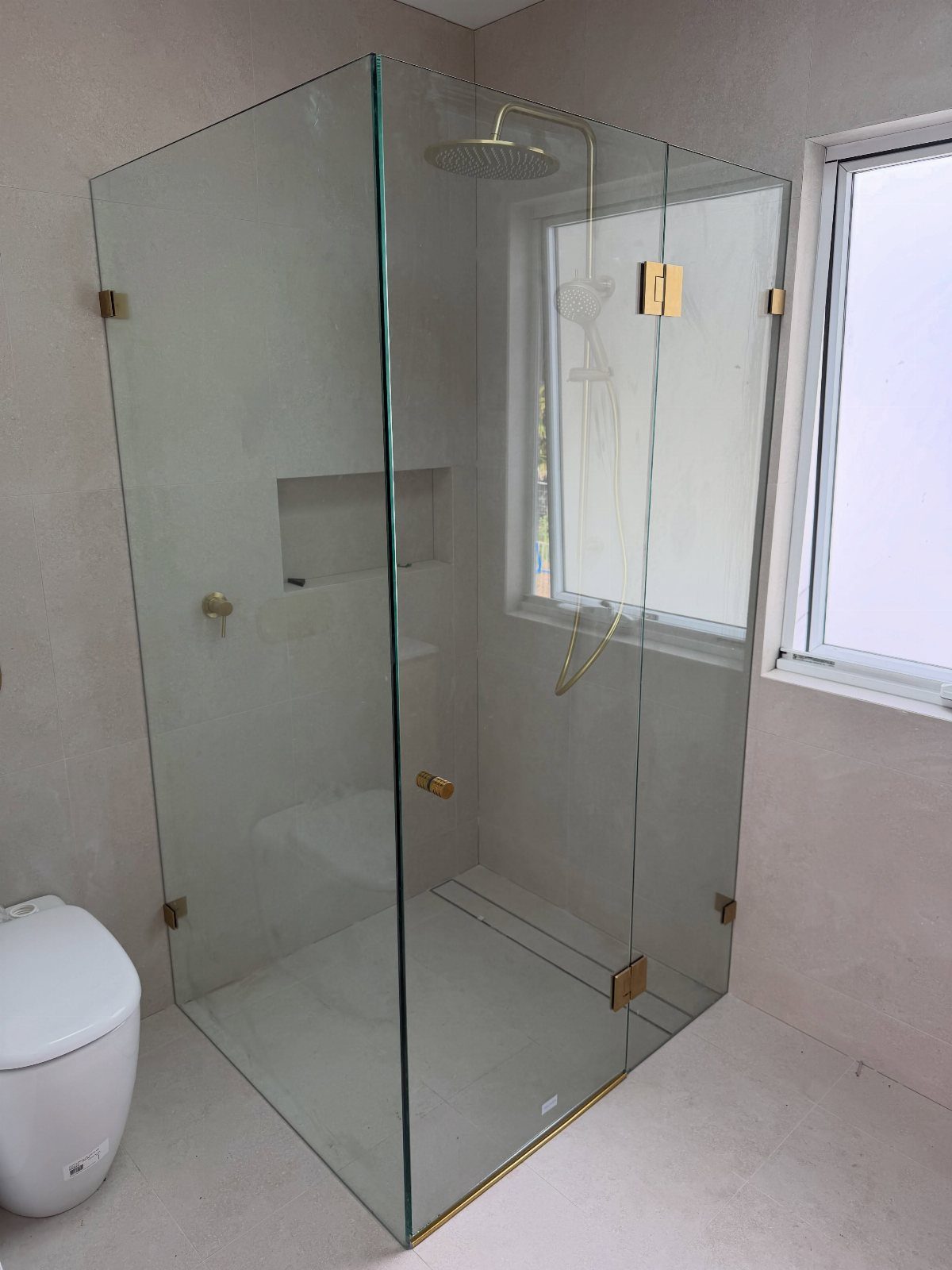 19 Teen Bathroom Ideas That Blend Style and Function 17 Frameless glass shower enclosure with gold hardware in a modern grey bathroom.