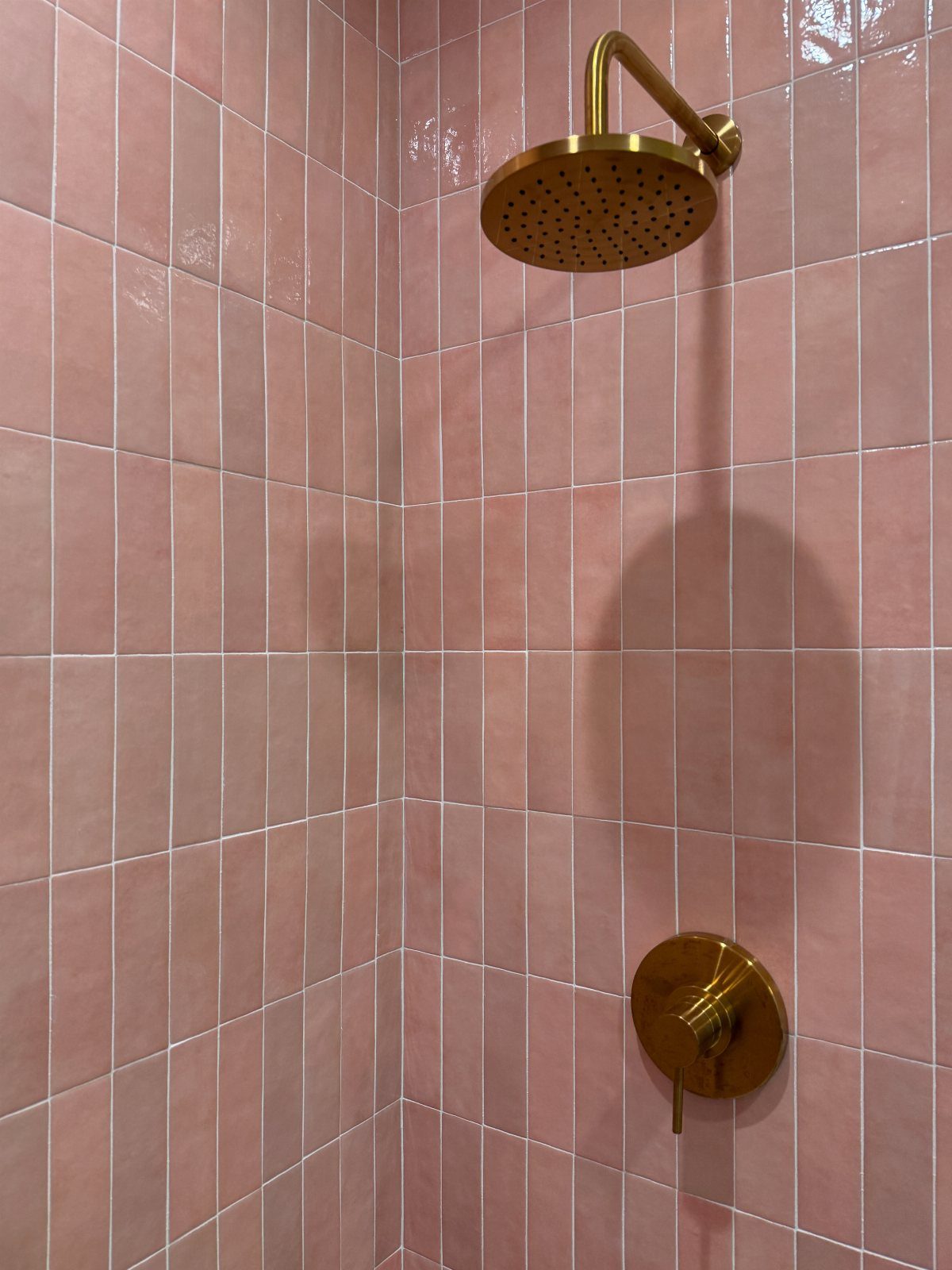 19 Teen Bathroom Ideas That Blend Style and Function 13 Pink vertical wall tiles with a gold rain shower head and gold faucet handle.