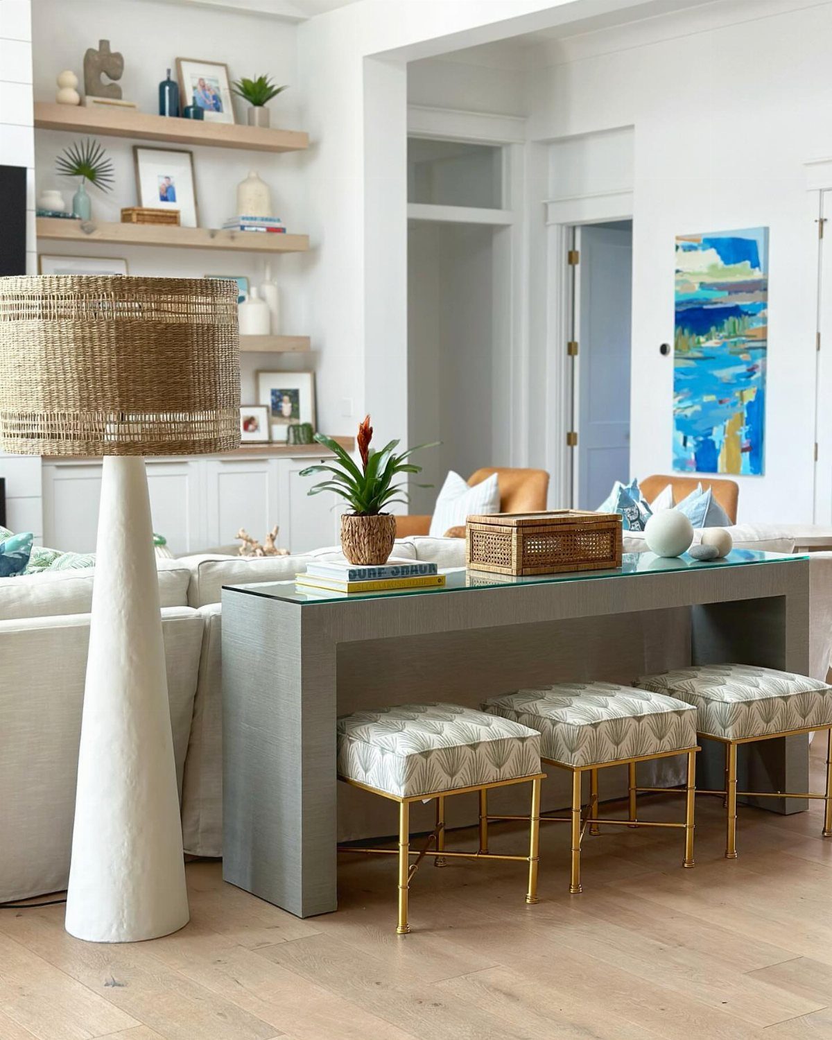 Three patterned stools with gold legs tucked under a grey console table.