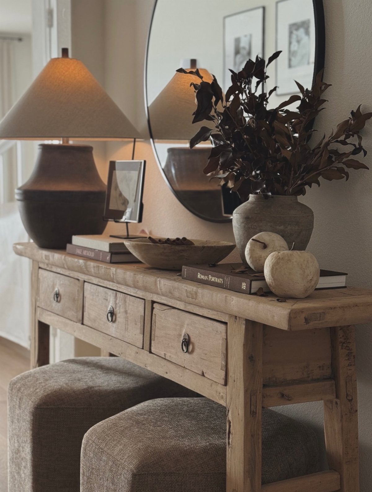 Rustic wooden console table with a lamp, mirror, and decorative bowls and books.
