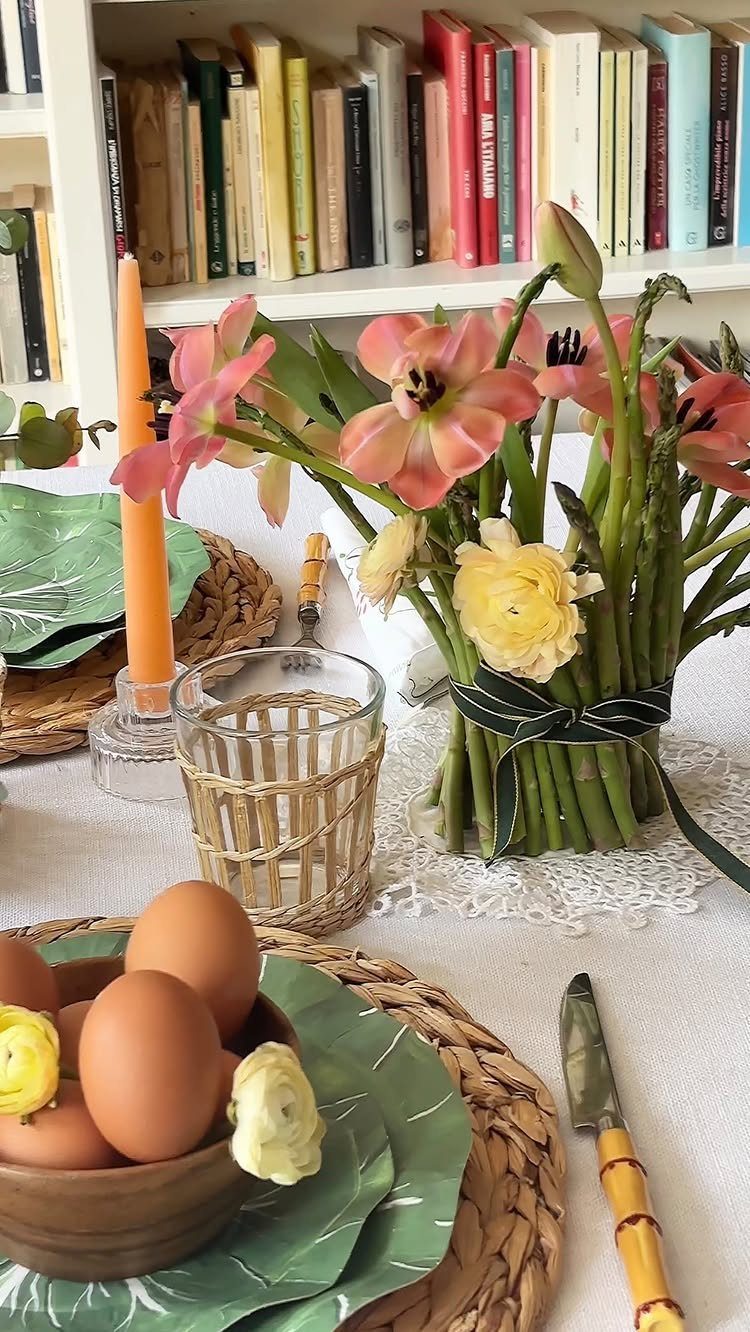 Spring table arrangement with pink tulips, yellow flowers, brown eggs, and orange candle.