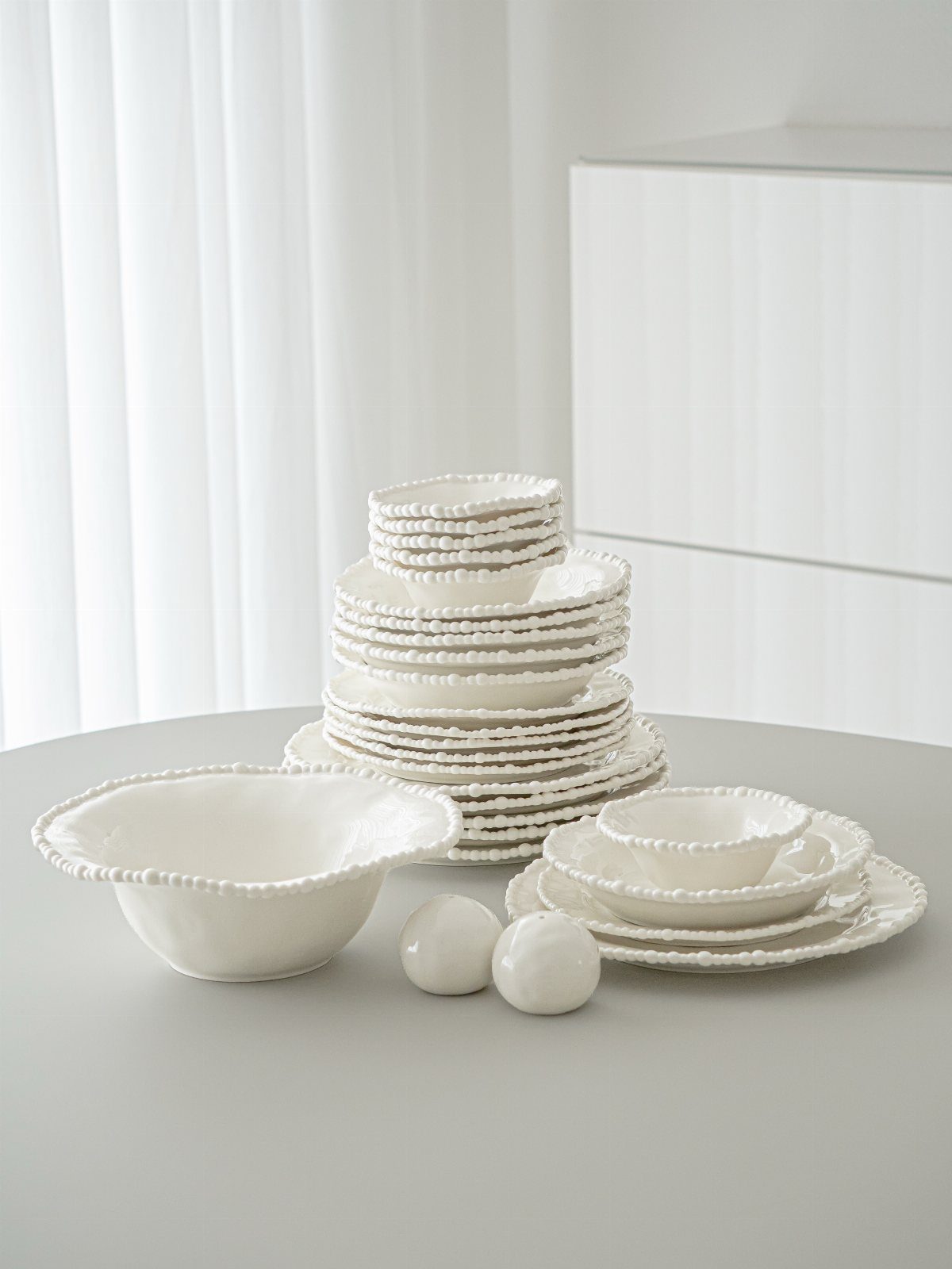 White ceramic dinnerware set with a decorative beaded border on the rims.