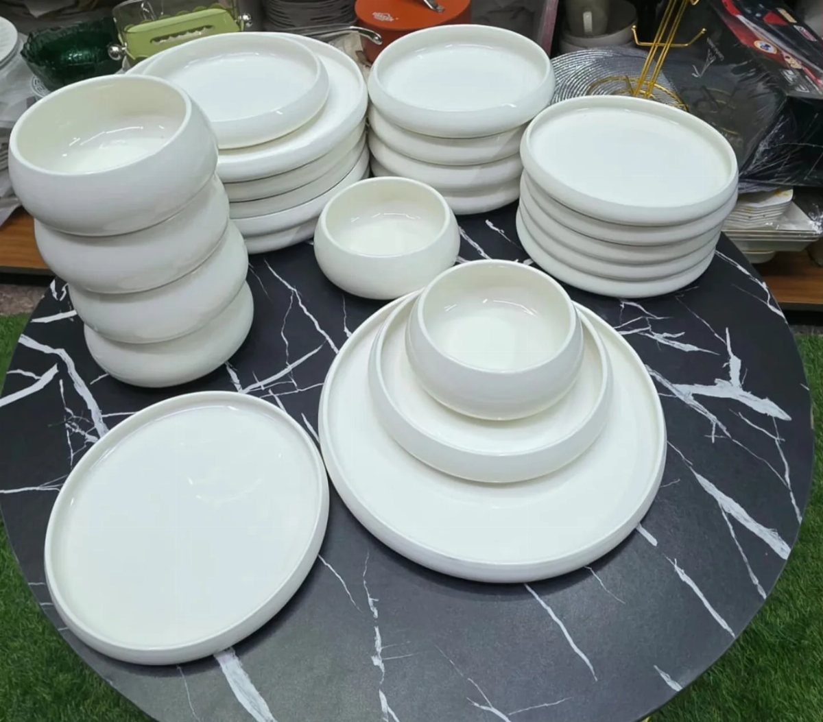 White glossy stoneware plates and bowls arranged on a black marble table