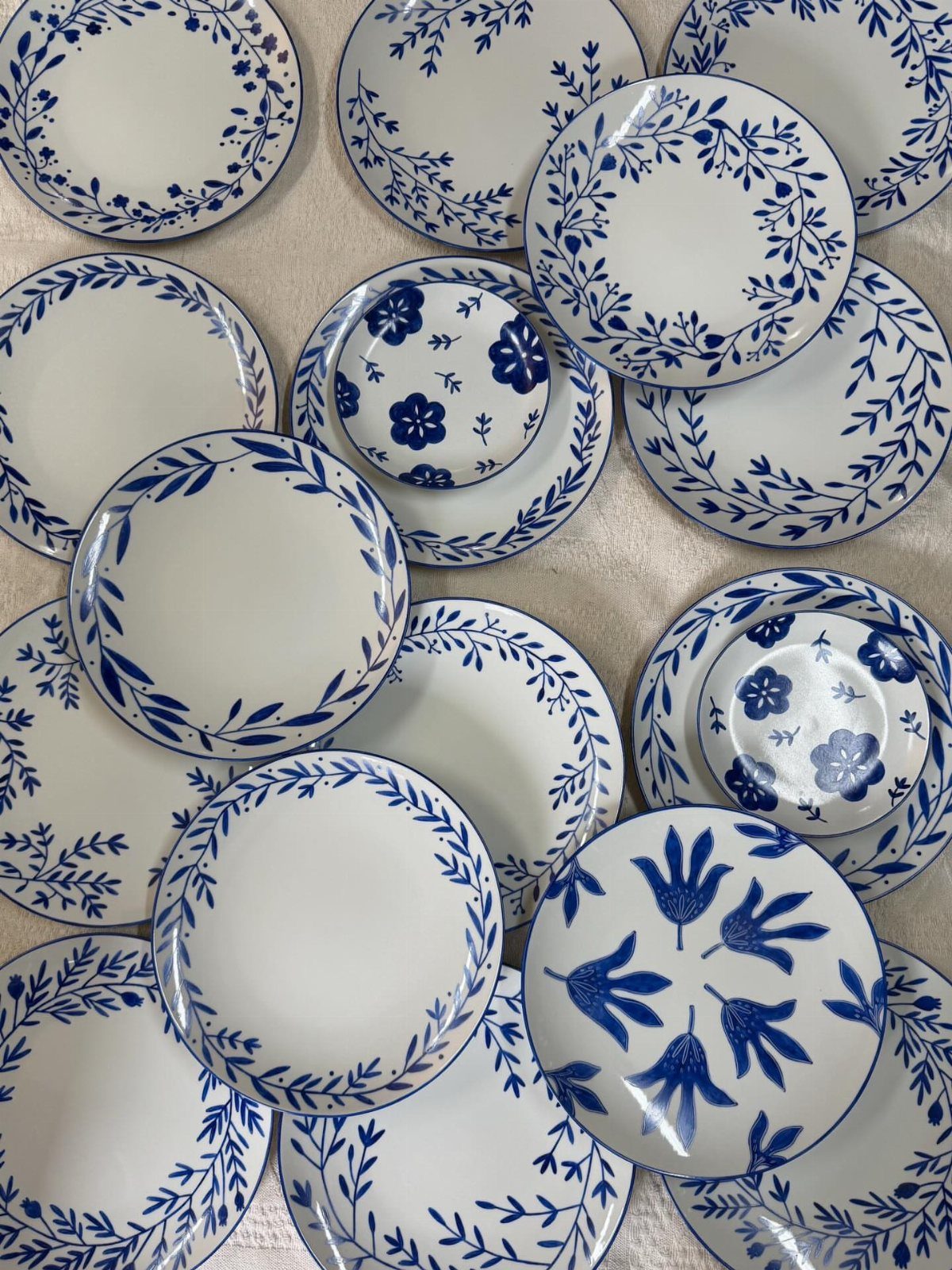 White stoneware plates and bowls with blue handpainted floral and leaf patterns.