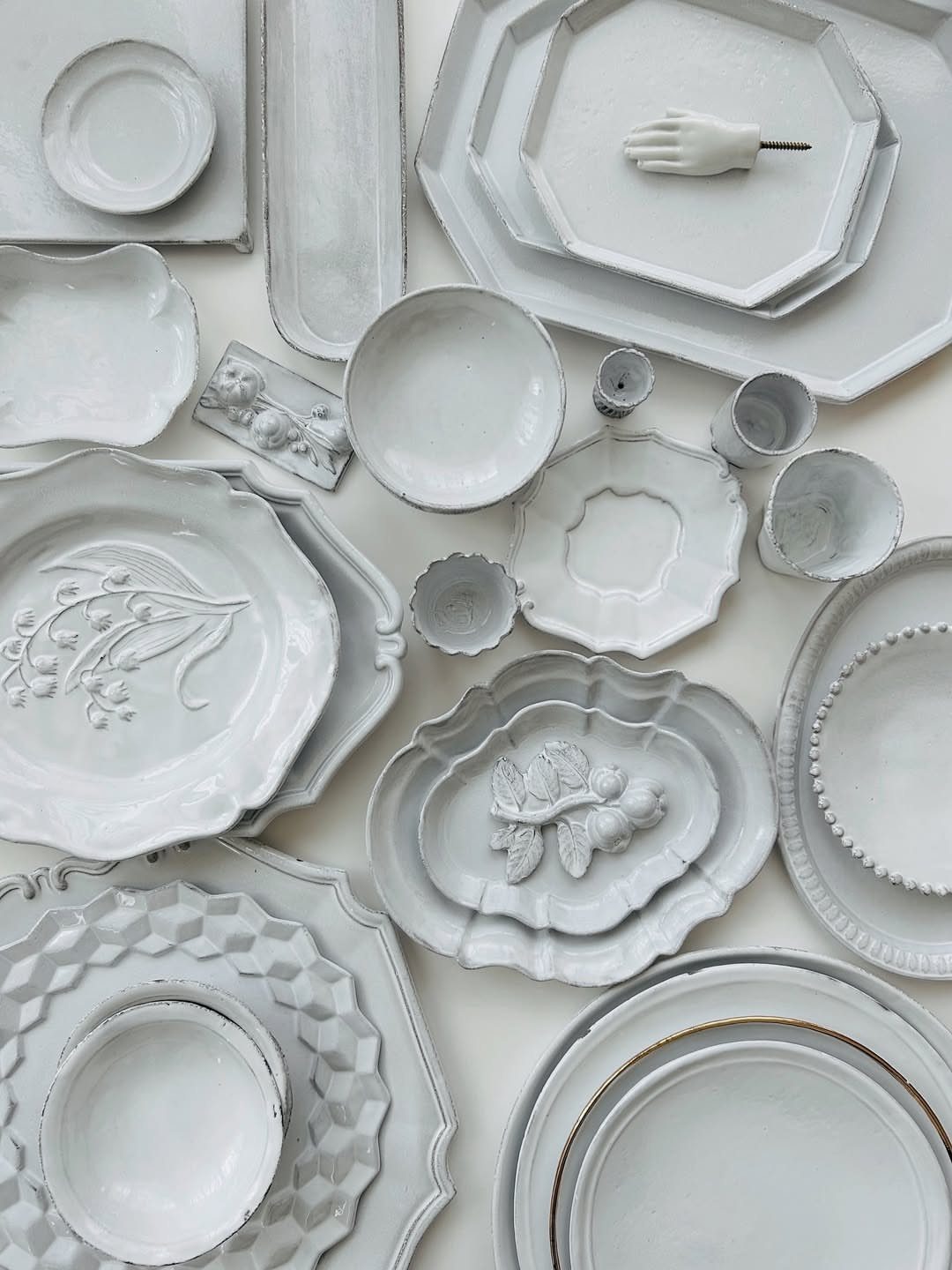 Various white stoneware plates and bowls of different shapes and textures on white background